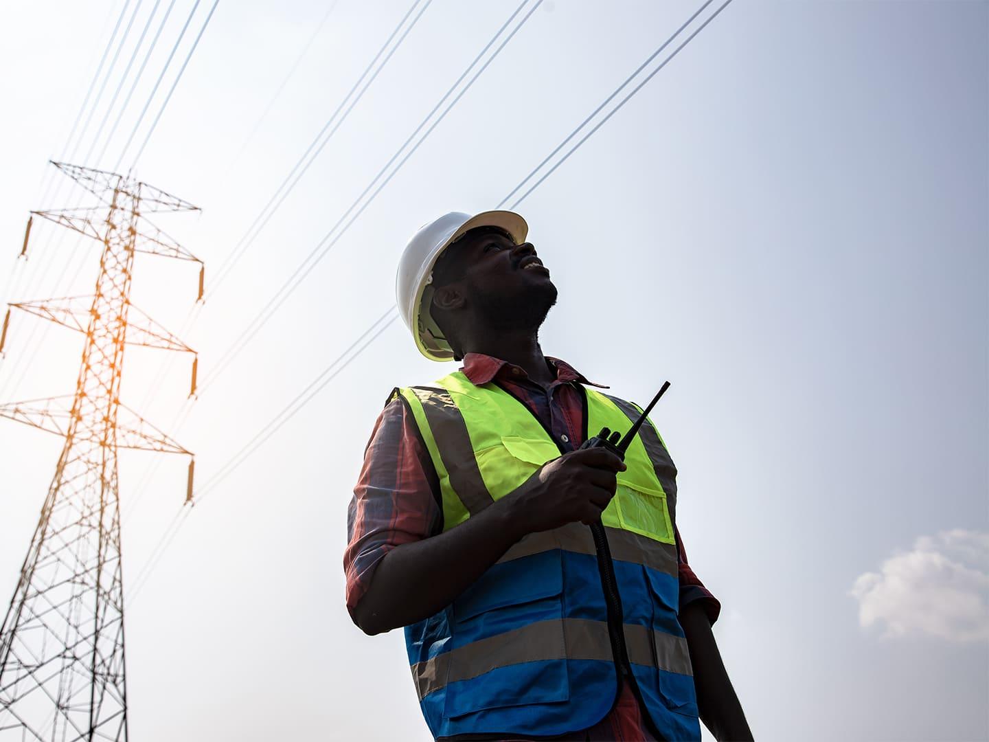 Homme qui inspecte le réseau électrique aérien